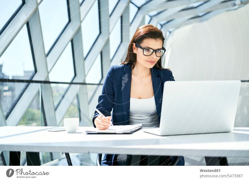 Businesswoman working at desk in modern office offices office room office rooms desks contemporary At Work businesswoman businesswomen business woman