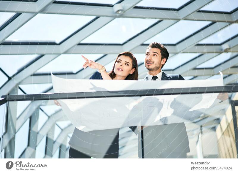 Businesswoman and businessman with plan talking in office offices office room office rooms Businessman Business man Businessmen Business men plans businesswoman