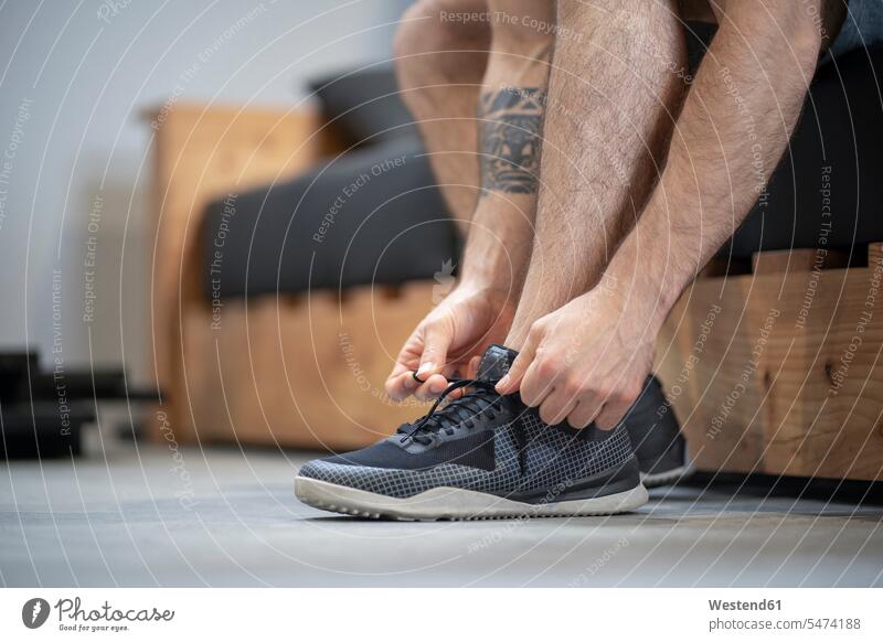 Close-up of man tying shoelace while sitting on bed at home color image colour image indoors indoor shot indoor shots interior interior view Interiors Spain