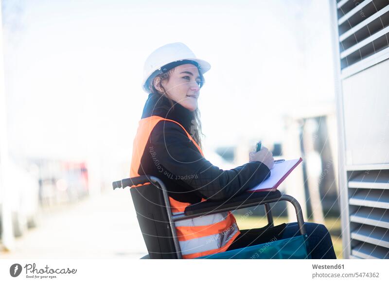 Young technician with safety helmet and vest in wheelchair working outdoors female technician female technicians Safety Helmet protective helmet wheelchairs