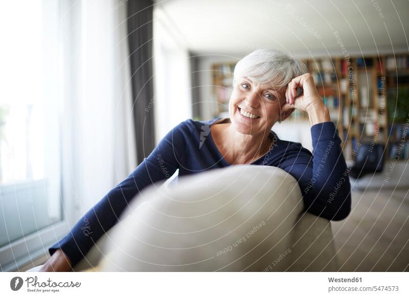 Smiling senior woman relaxing while sitting on sofa color image colour image indoors indoor shot indoor shots interior interior view Interiors day daylight shot