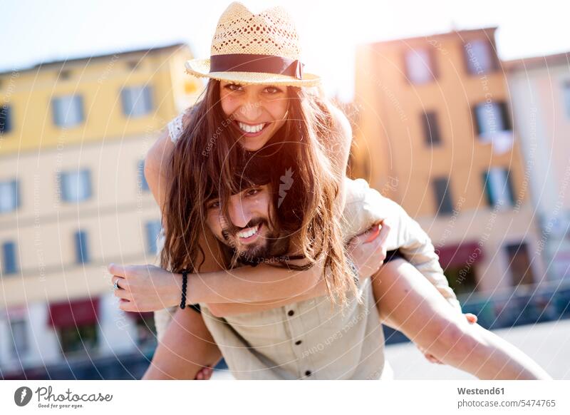 Portrait of happy young man giving his girlfriend a piggyback ride Girlfriends girl friend girl friends smiling smile men males piggy-back pickaback