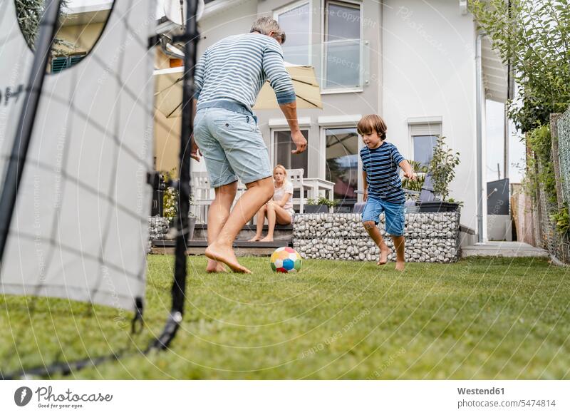 Father and son playing football in garden balls footballs soccer balls run summer time summertime summery Ardor Ardour enthusiasm enthusiastic excited delight