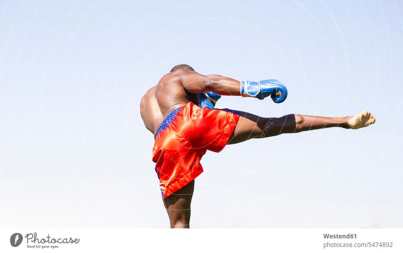Active male athlete doing boxing exercise against clear sky on sunny day color image colour image outdoors location shots outdoor shot outdoor shots