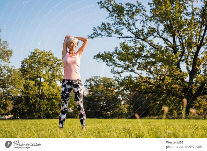 Senior woman stretching on rural meadow meadows females women country countryside senior women elder women elder woman old senior woman Adults grown-ups