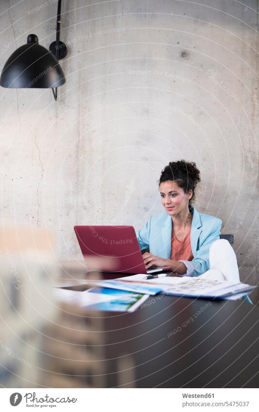 Businesswoman sitting at table in a loft using laptop Table Tables Laptop Computers laptops notebook businesswoman businesswomen business woman business women