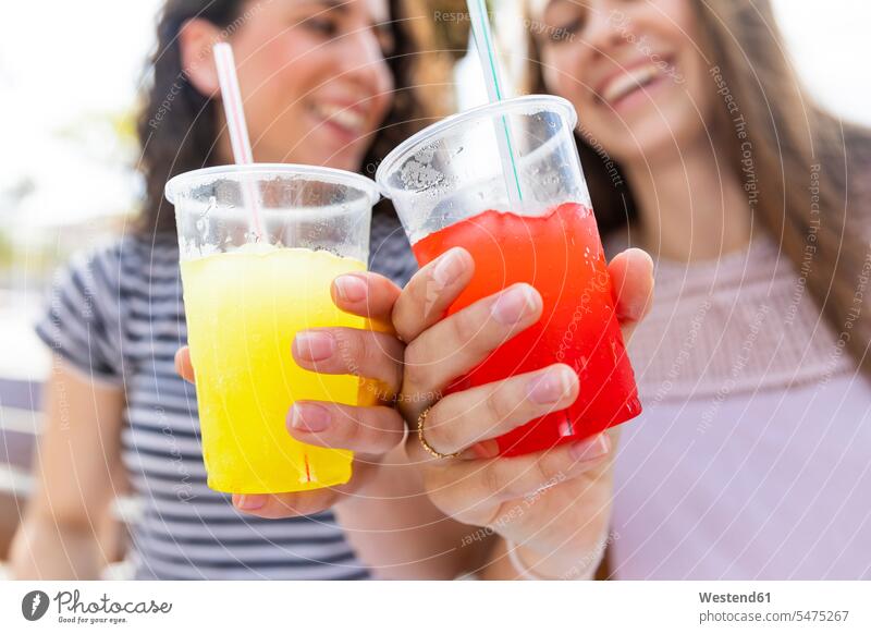 Close-up of two female friends enjoying a fresh slush slushies slushy Freshly indulgence enjoyment savoring indulging Drink beverages Drinks Beverage