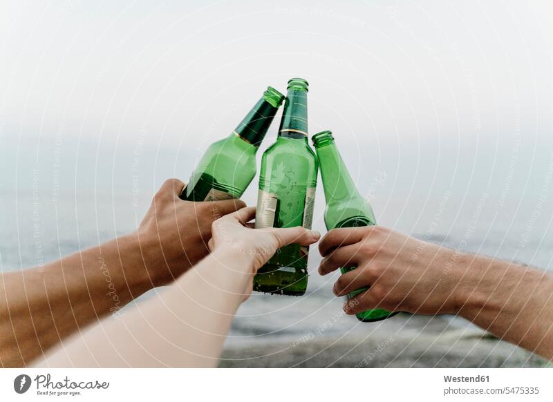 Hands of three friends making celebratory toast with beer bottles outdoors location shots outdoor shot outdoor shots Selective focus Differential Focus Bulgaria