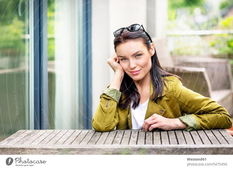 Portrait of a young woman, with sunglasses in her hair, sitting at outdoor table portrait portraits Table Tables sun glasses Pair Of Sunglasses smiling smile