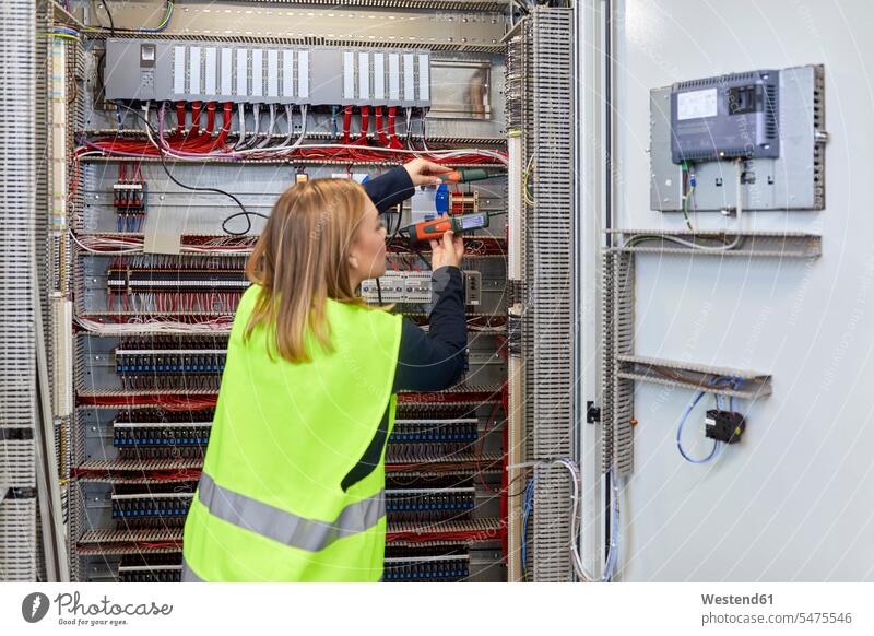 Female electrician working with voltmeter at fuse box human human being human beings humans person persons caucasian appearance caucasian ethnicity european 1