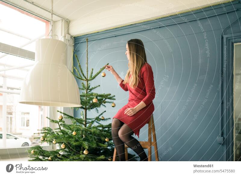 Woman sitting on ladder in a loft decorating Christmas tree lofts X-Mas yule Xmas X mas Christmas trees woman females women decorate decorated Seated ladders