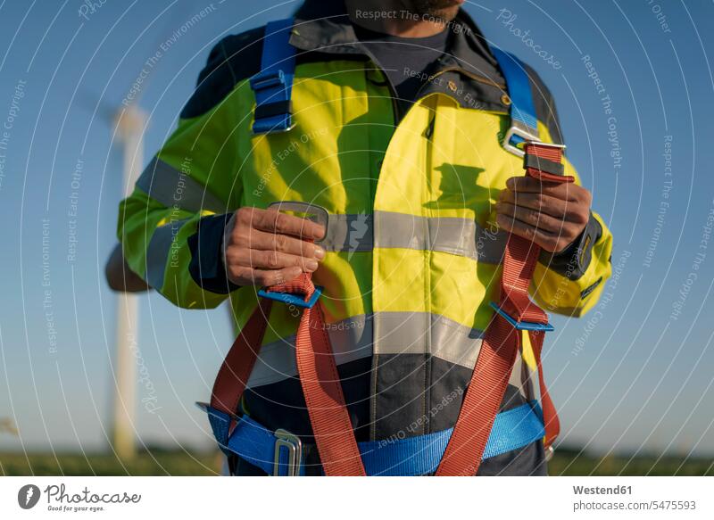 Close-up of technician at a wind farm putting on climbing harness wind park technicians put on wind power plant wind turbine wind turbines wind energy