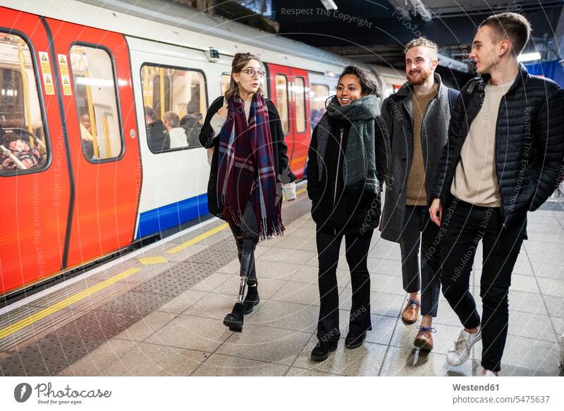 Friends walking at subway station platfom friends mate touristic tourists coat coats jackets scarfs scarves railroad railroads Railways subway line subway lines