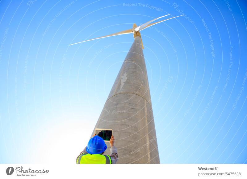 Low angle view of technician taking picture with a tablet of wind turbine wind turbines photographing digitizer Tablet Computer Tablet PC Tablet Computers iPad