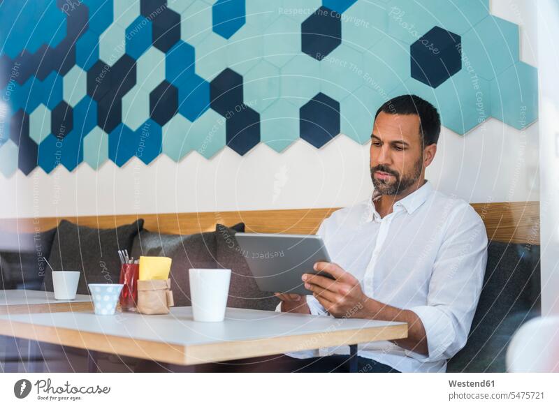 Man using tablet in a cafe man men males digitizer Tablet Computer Tablet PC Tablet Computers iPad Digital Tablet digital tablets Adults grown-ups grownups