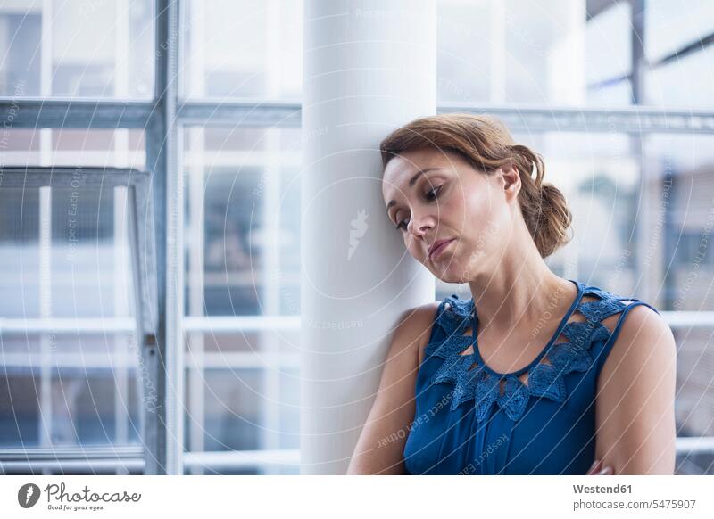 Pensive businesswoman leaning on column in office color image colour image business people businesspeople Business Professional Business Professionals