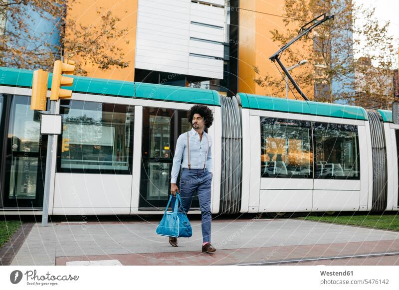 Spain, Barcelona, man with bag crossing the street in front of a tramway road streets roads bags tramways streetcars trams men males railway railroad Adults