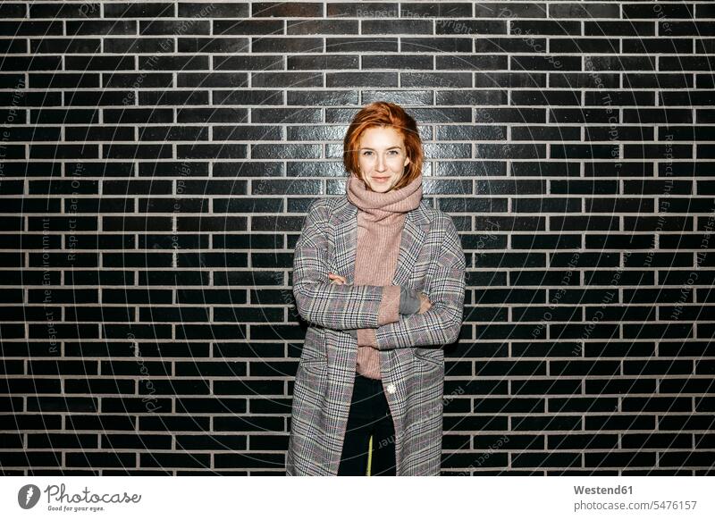 Portrait of a smiling young woman standing at a black wall smile portrait portraits walls females women Adults grown-ups grownups adult people persons