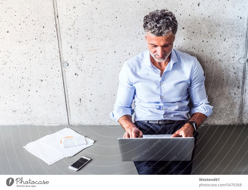 Mature businessman sitting on the floor using laptop Businessman Business man Businessmen Business men floors Laptop Computers laptops notebook Seated