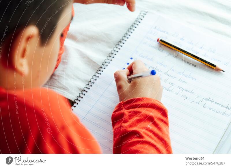 Young boy writing in book with pen during homeschooling color image colour image 10-11 years 10 to 11 years children kid kids people human being human beings