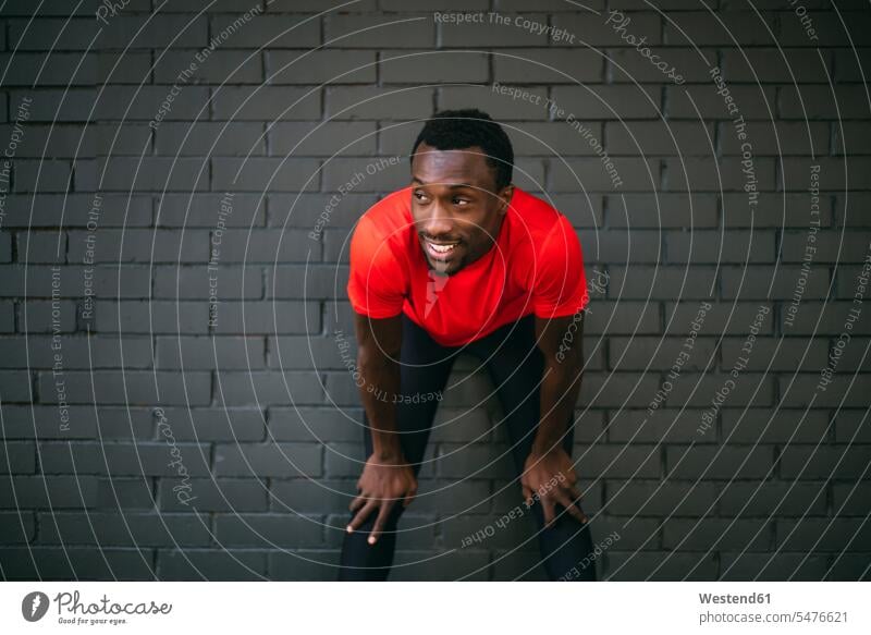 Smiling young sportive man taking a break from workout in front of a brick wall human human being human beings humans person persons 1 one person only