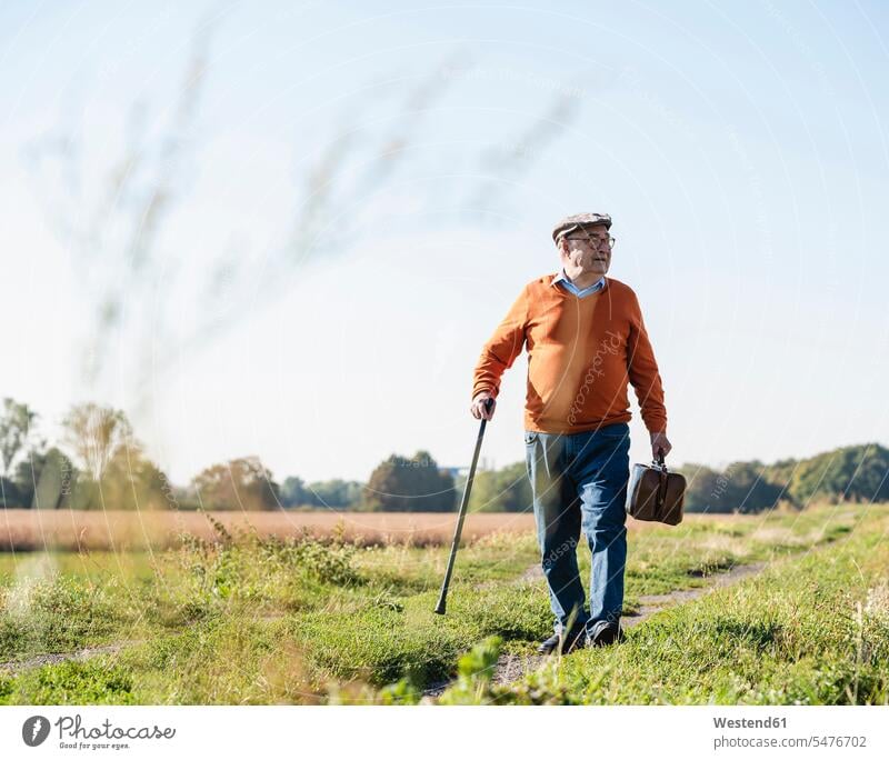 Senior man carrying traveling bag, walking in the fields leaving leave walking away Field Fields farmland travelling bag travelling bags traveling bags going