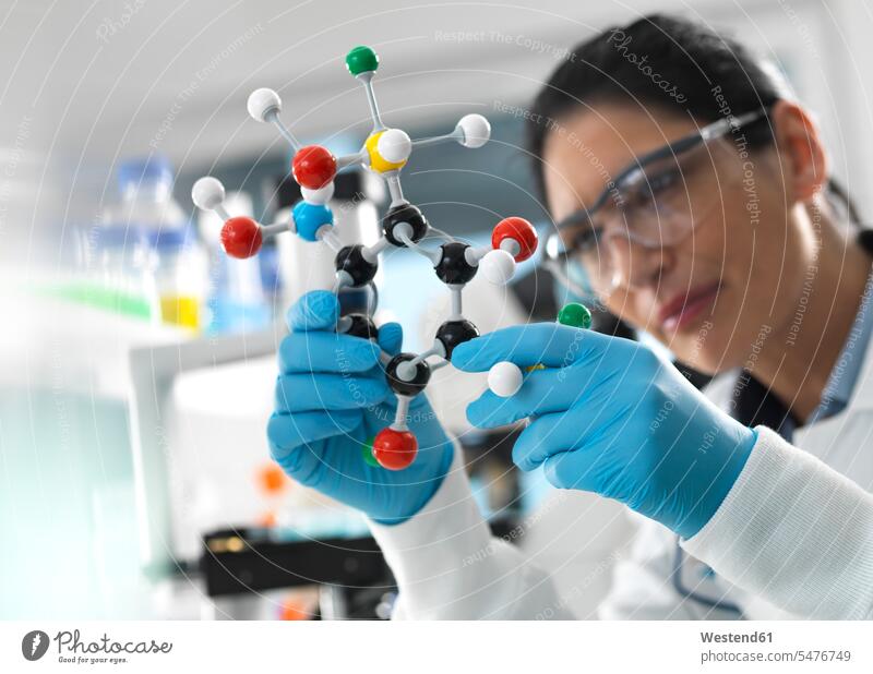 Biotech Research, Scientist examining a ball and stick molecular model of a chemical formula during a experiment Occupation Work job jobs profession
