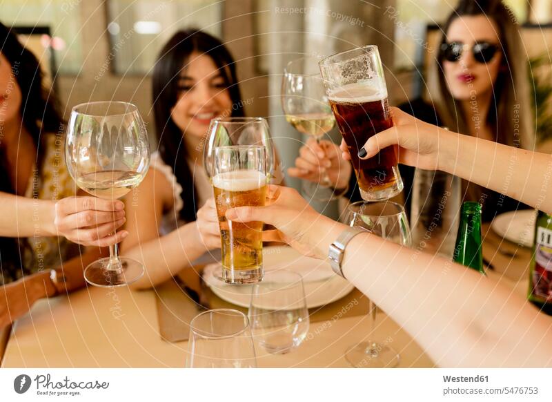 Happy female friends toasting drinks while sitting at table in restaurant color image colour image Spain indoors indoor shot indoor shots interior interior view
