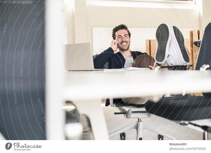 Young businessman sitting in office, with feet on desk, talking on the phone Occupation Work job jobs profession professional occupation business life