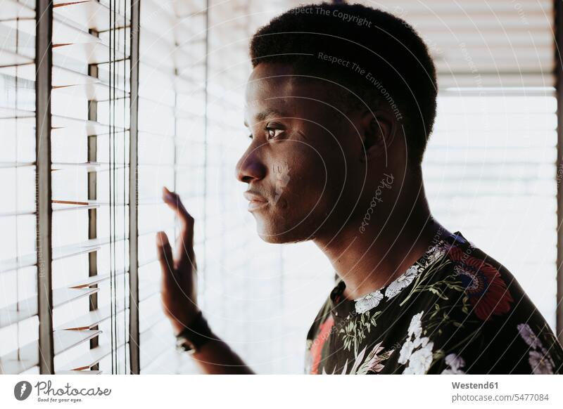 Pensive young man looking out of window pensive thoughtful Reflective contemplative windows watching men males view seeing viewing Adults grown-ups grownups