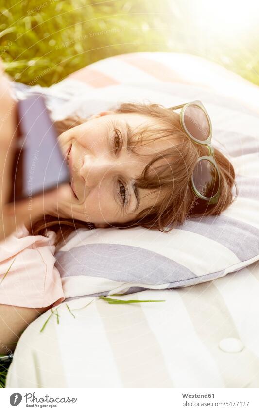 Relaxed woman lying on a meadow using cell phone human human being human beings humans person persons caucasian appearance caucasian ethnicity european 1