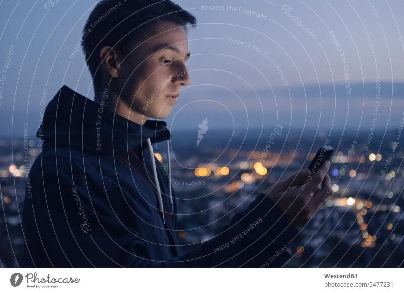 Young man looking at shining smartphone in the evening eyeing men males Smartphone iPhone Smartphones shine view seeing viewing Adults grown-ups grownups adult