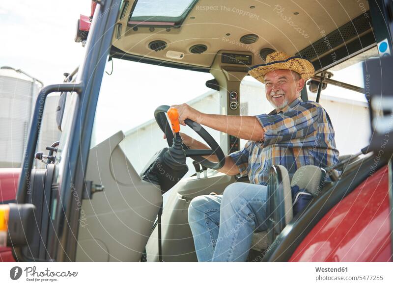 Portrait of smiling senior farmer on tractor agriculturists farmers senior men senior man elder man elder men senior citizen smile portrait portraits males