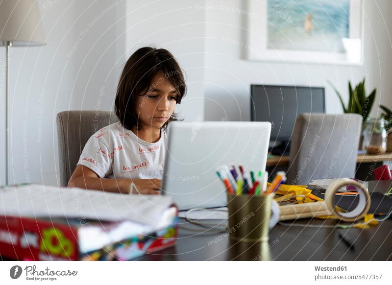 Portrait of boy sitting at table in the living room using laptop Tables pencil pencils pens computers Laptop Computer Laptop Computers laptops notebook at home