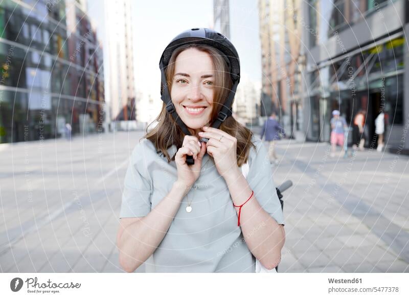 Woman putting on a helmet, e-scooter in the background human human being human beings humans person persons caucasian appearance caucasian ethnicity european 1