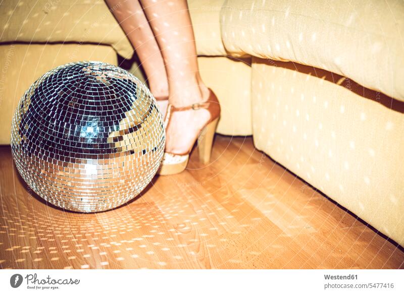 Young woman wearing high heels standing by disco ball on floor in party color image colour image indoors indoor shot indoor shots interior interior view