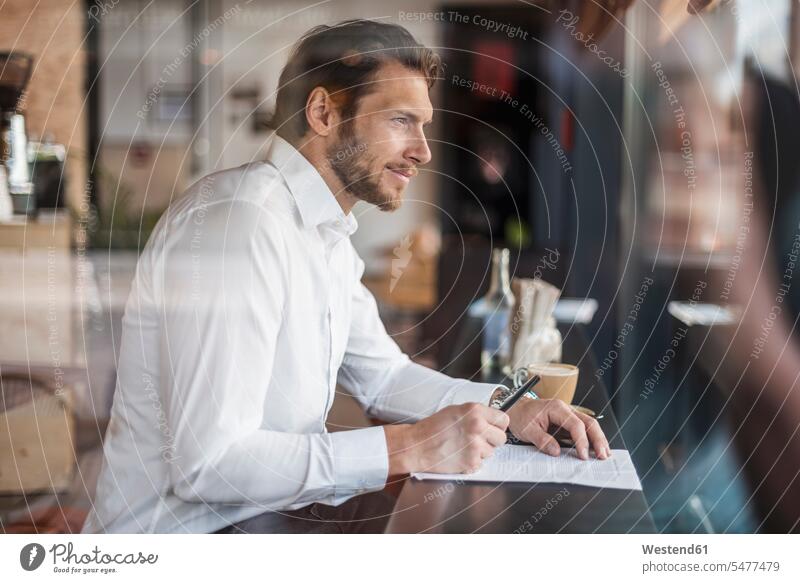 Businessman in a cafe taking notes making a note note taking Business man Businessmen Business men business people businesspeople business world business life