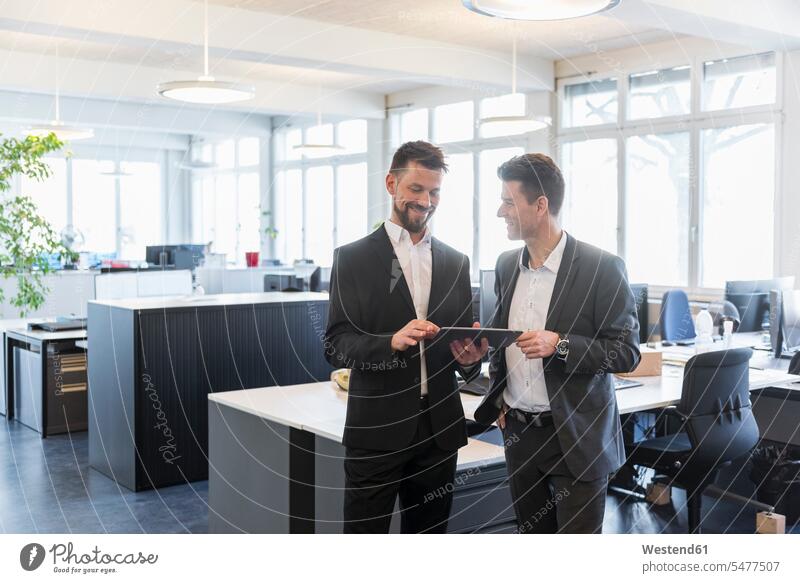 Two businessmen standing in office, discussing solutions, using digital tablet digitizer Tablet Computer Tablet PC Tablet Computers iPad Digital Tablet