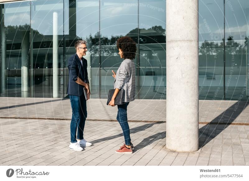 Two colleagues talking outside office building speaking office buildings built structure built structures Spain break side view sideview View From Side