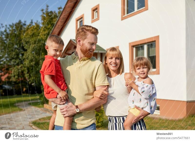 Portrait of happy family in garden of their home gardens domestic garden portrait portraits happiness house houses families building buildings built structure