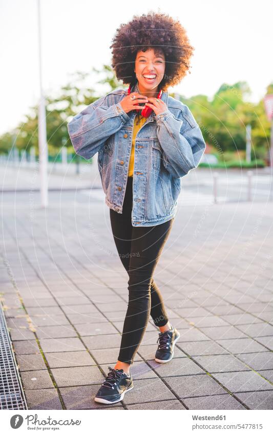 Portrait of happy young woman with afro hairdo in the city human human being human beings humans person persons curl curled curls curly hair headphone headset