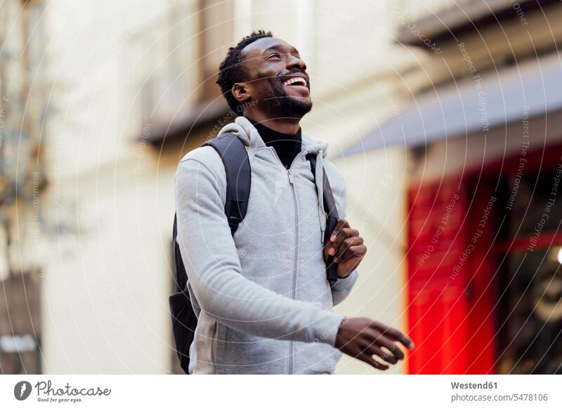 Smiling man carrying backpack while walking outdoors color image colour image location shots outdoor shot outdoor shots day daylight shot daylight shots