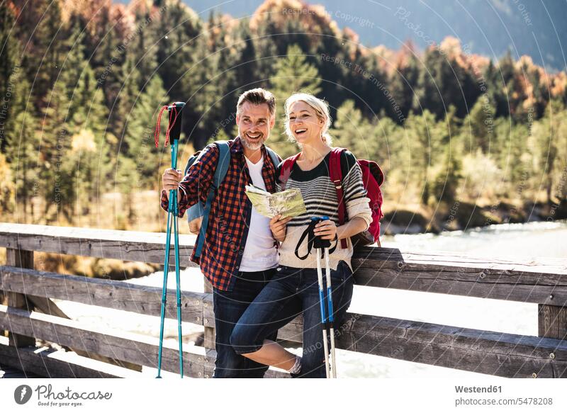 Austria, Alps, happy couple on a hiking trip with map on a bridge caucasian caucasian appearance caucasian ethnicity european White - Caucasian mature men