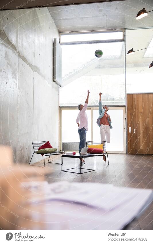 Casual businessman and businesswoman playing basketball in a loft businesswomen business woman business women Businessman Business man Businessmen Business men