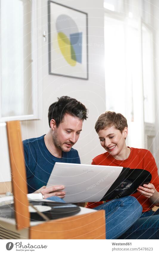 Couple sitting at home, listening to old records vinyl record music together couple twosomes partnership couples analogue Media people persons human being