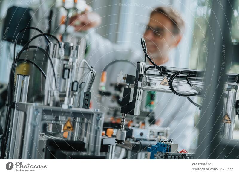 Close-up of machinery with male scientist in background at factory color image colour image indoors indoor shot indoor shots interior interior view Interiors