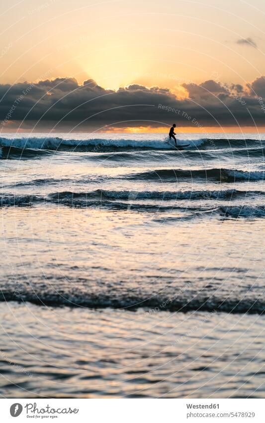Silhouette man surfing with paddleboard on sea against sky during dawn color image colour image outdoors location shots outdoor shot outdoor shots