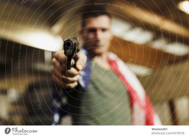 Close-up of man wearing American flag aiming with a gun pistol guns pistols american ensign national flags ensigns men males shooting weapon arms weapons banner