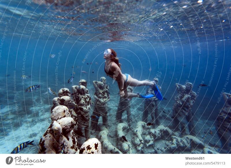 Woman swimming near underwater sculpture made by Jason deCaires Taylor, Gili Meno island, Bali, Indonesia rounding roundings circles circular broken-up