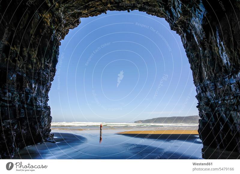 Woman standing in the giant Cathedral caves, The Catlins, South Island, New Zealand solitary reclusive reclusively enormous gigantic humongous tremendous little